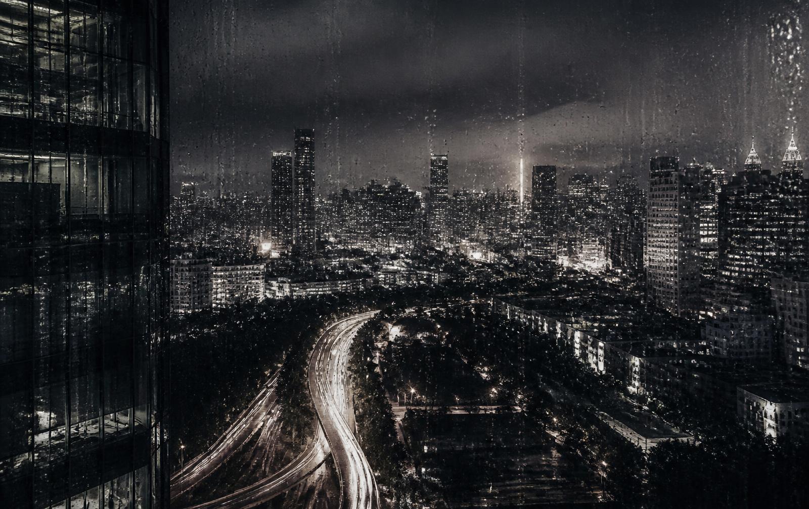 Night city seen through rain-flecked glass from a high floor